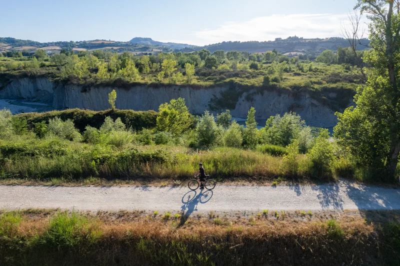 Ciclista su strada bianca nel paesaggio collinare romagnolo
