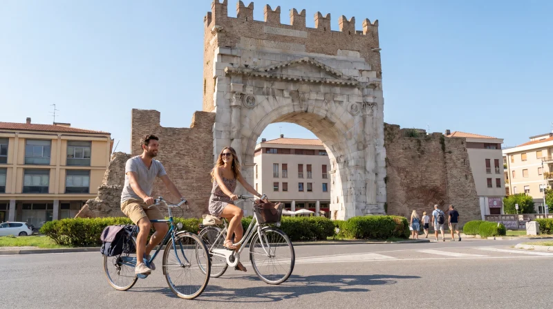 Coppia in bicicletta davanti all’Arco d’Augusto a Rimini