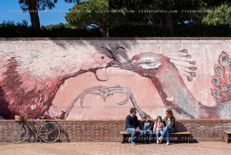 Famiglia e bicicletta davanti a un murale artistico a Rimini