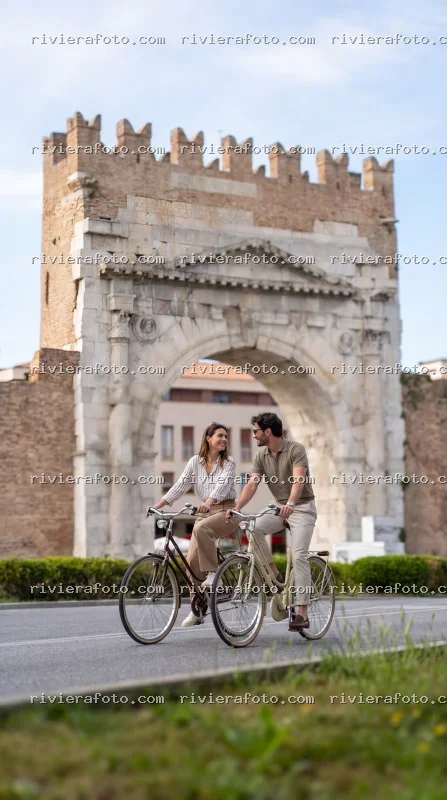 Coppia in bicicletta davanti all’Arco d’Augusto a Rimini