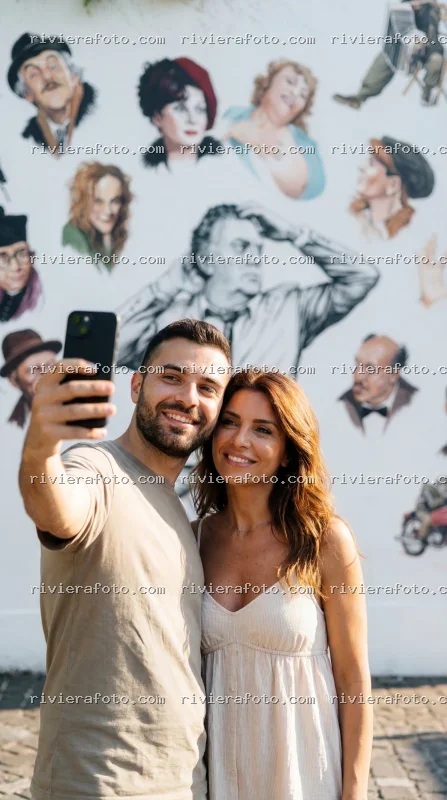 Coppia in selfie davanti al murale di Federico Fellini a Rimini