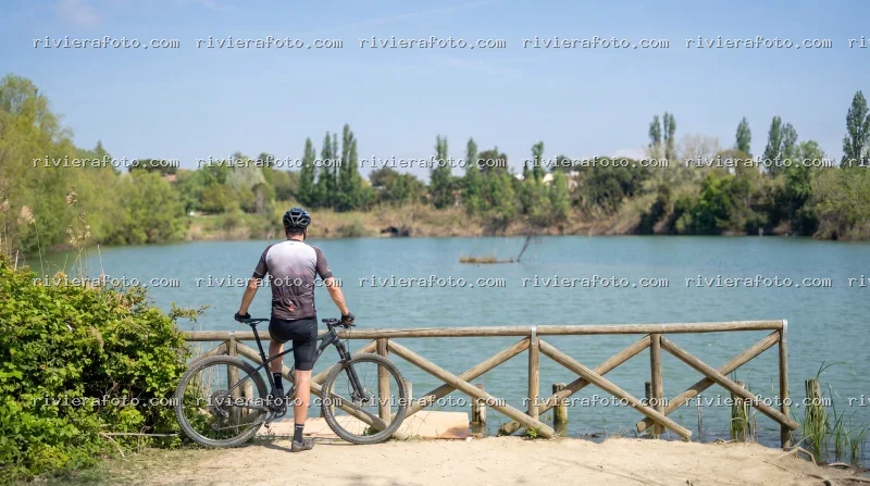 Ciclista in pausa contemplativa in un’oasi naturale di Rimini, parco della cava