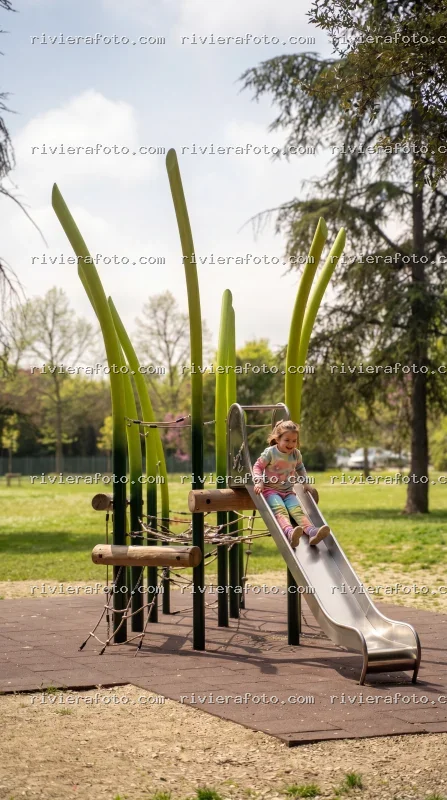 Bambina che gioca su uno scivolo in un parco pubblico di Rimini