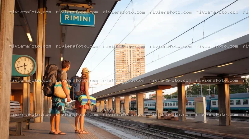 Viaggiatori in attesa alla stazione di Rimini al tramonto