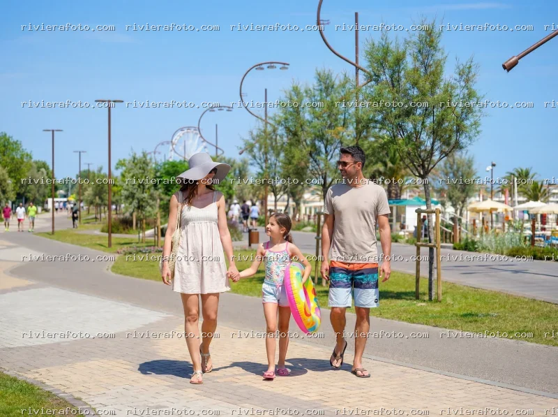 Famiglia in passeggiata sul lungomare di Rimini con vista sulla ruota panoramica