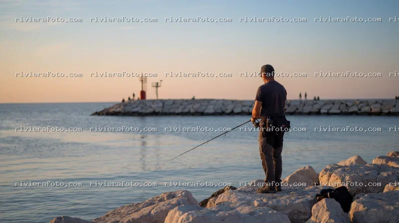 Pescatore al tramonto sul molo di Rimini, sulla Riviera Romagnola