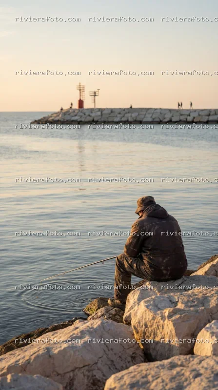 Pescatore al tramonto sul molo di Rimini, sulla Riviera Romagnola