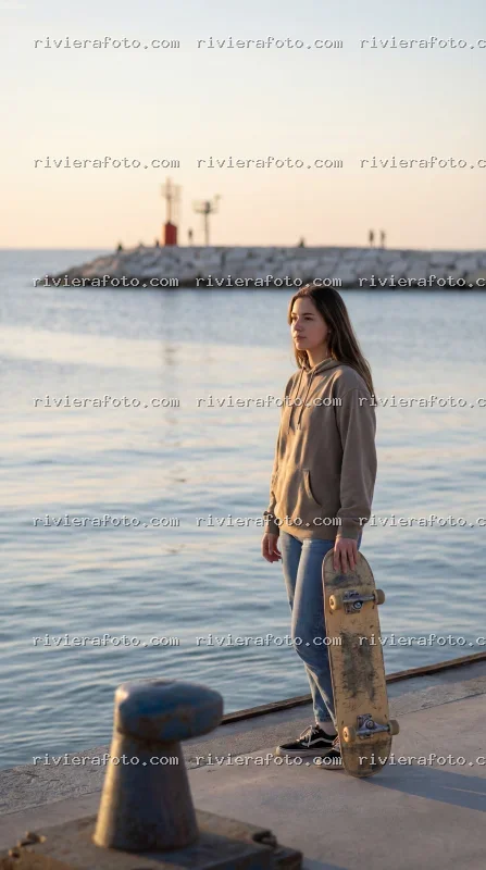 Ragazza con skateboard al porto di Rimini, sulla Riviera Romagnola al tramonto