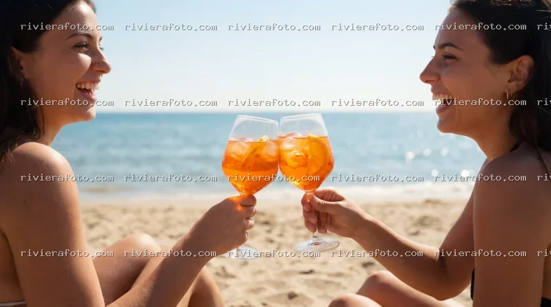 Amiche brindano con Aperol Spritz sulla spiaggia di Rimini nella Riviera Romagnola