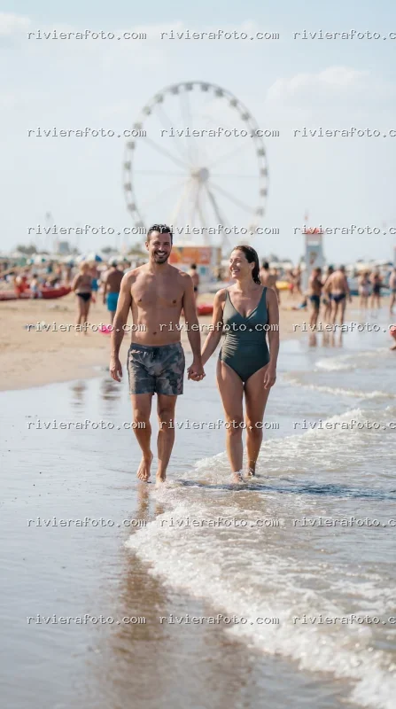 Coppia in spiaggia con ruota panoramica a Rimini