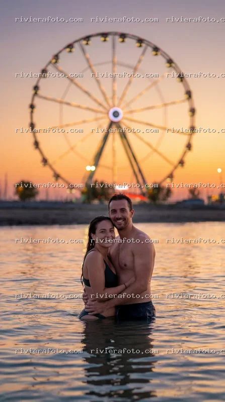 Coppia al tramonto con ruota panoramica a Rimini sulla Riviera Romagnola