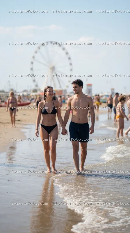 Coppia passeggia sulla spiaggia di Rimini con Ruota Panoramica