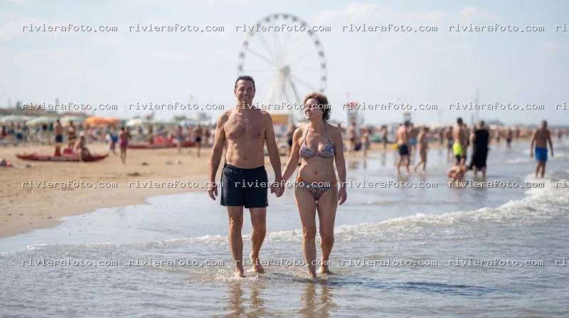 Coppia sulla spiaggia con ruota panoramica a Rimini