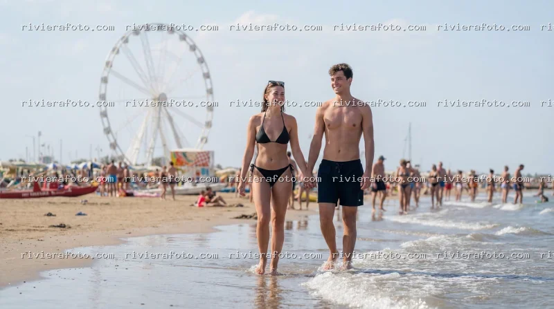 Coppia in spiaggia a Rimini sulla Riviera Romagnola con ruota panoramica