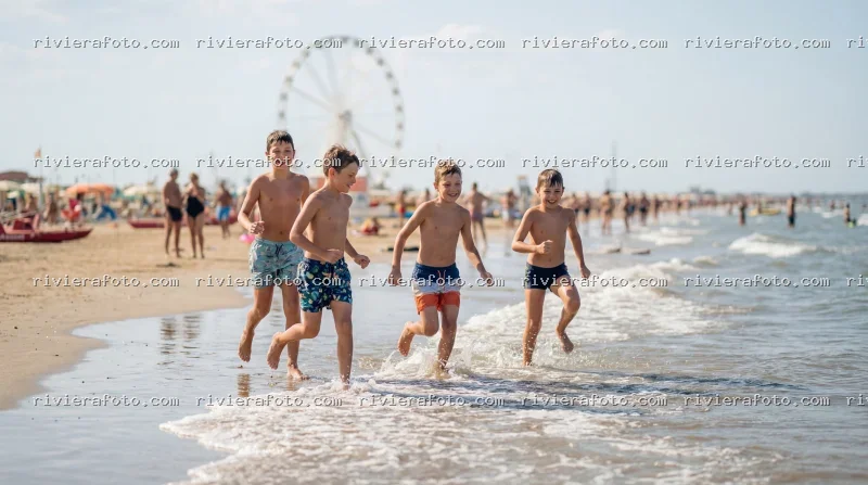 Bambini giocano in spiaggia a Rimini con ruota panoramica sullo sfondo