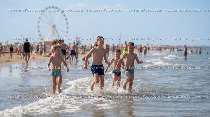 Bambini giocano in spiaggia a Rimini con ruota panoramica sullo sfondo