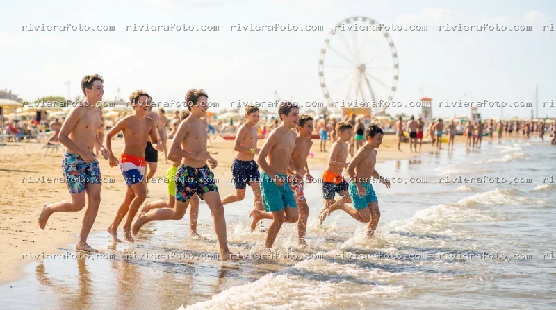 Ragazzi giocano sulla spiaggia di Rimini con vista sulla Ruota Panoramica
