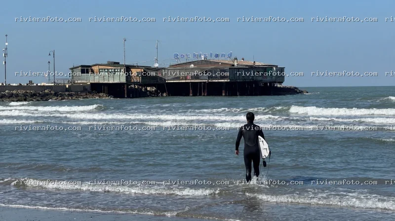 Surfista in mare con Rockisland sullo sfondo a Rimini